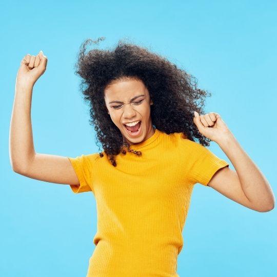Afrohiuksinen nainen tuulettaa keltaisessa paidassa turkoosilla taustalla