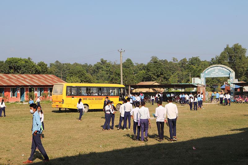 Nepalilaisia oppilaita ja keltainen koulubussi koulun pihalla.