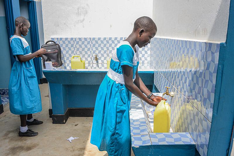 Ugandalainen koulutyttö pesee käsiään wc:ssä