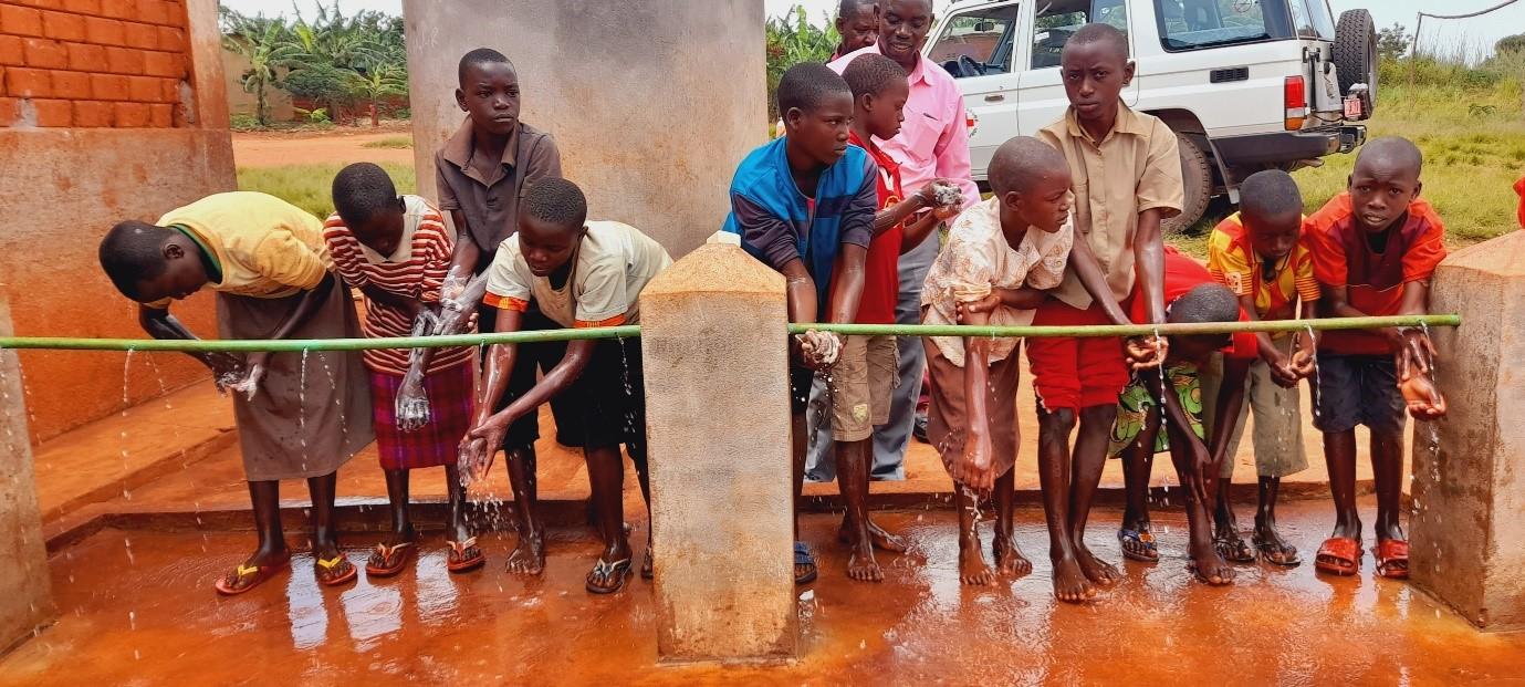 Kiningarian koulun lapsia pesemässä käsiä vestipisteellä